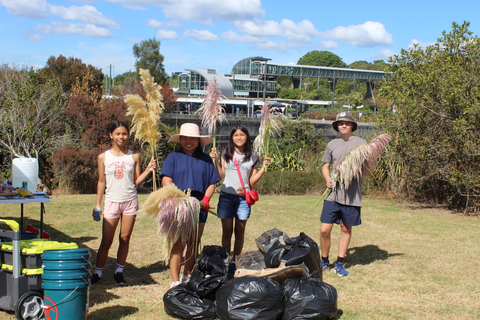 Volunteers with bags of cleared weeds beside Lake Pupuke