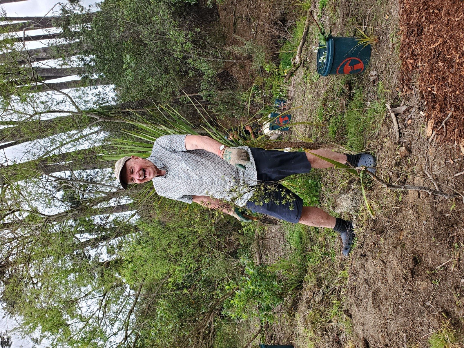A volunteer smiling while planting natives along a stream bank